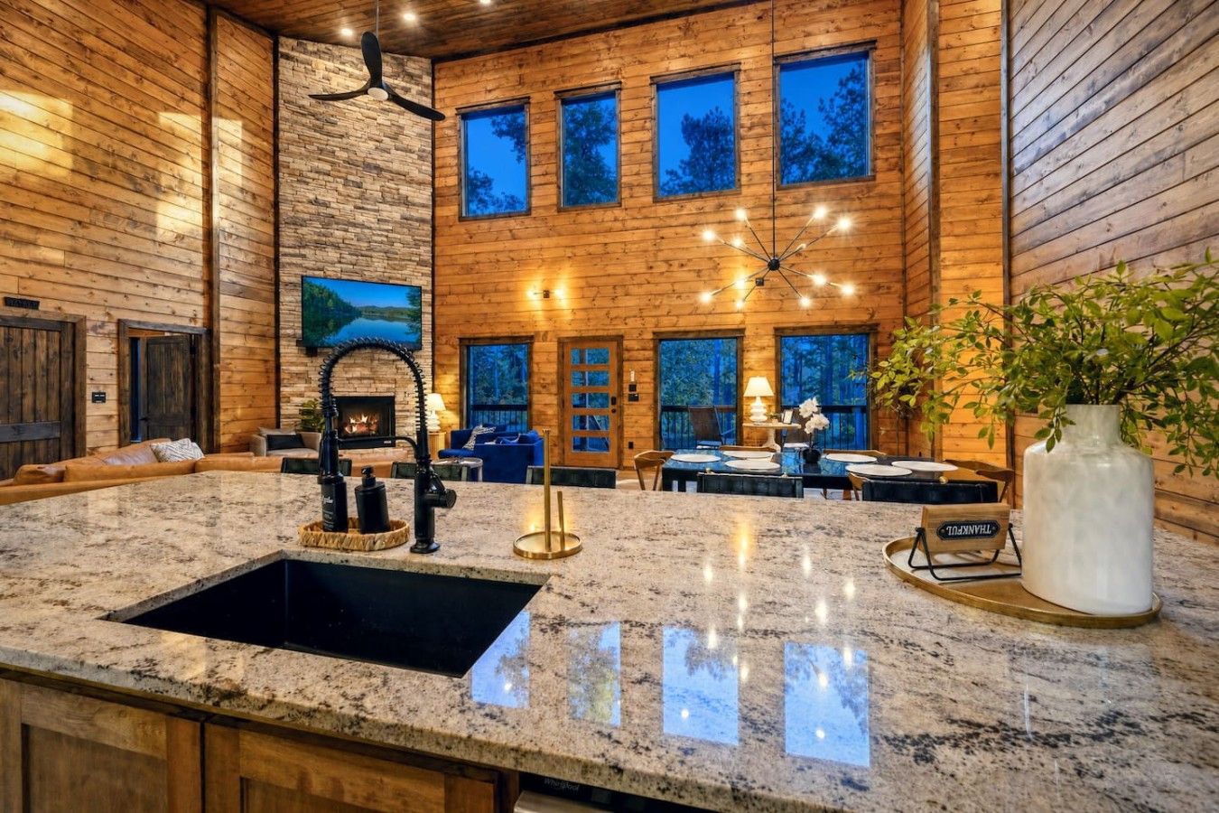 A modern kitchen with granite countertops, a black sink, and a dining area with a table set for four.