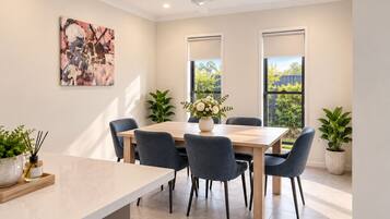 Un espace repas moderne avec une table en bois, six chaises et deux plantes en pot.