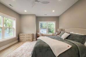 A bedroom with a bed, a nightstand, a dresser, a window, and a ceiling fan. - Irish Victory House | 5BR/4BA (South Bend)