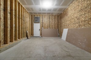 A room under construction with exposed wooden studs, a white door, and a large window. - Irish Victory House | 5BR/4BA (South Bend)