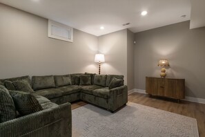 Ein Wohnzimmer mit einem Ecksofa, einem Beistelltisch und einer Lampe.