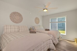 Ein Schlafzimmer mit zwei Betten, einem Deckenventilator und einem großen Fenster.