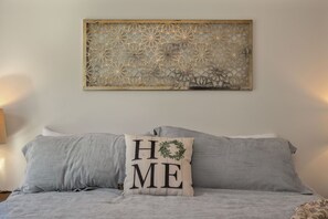 A bedroom with a bed, a decorative wall piece, and a pillow with 'HOME' text. - Luxury Legacy Retreat | Sleeps 10 | South Bend (South Bend)
