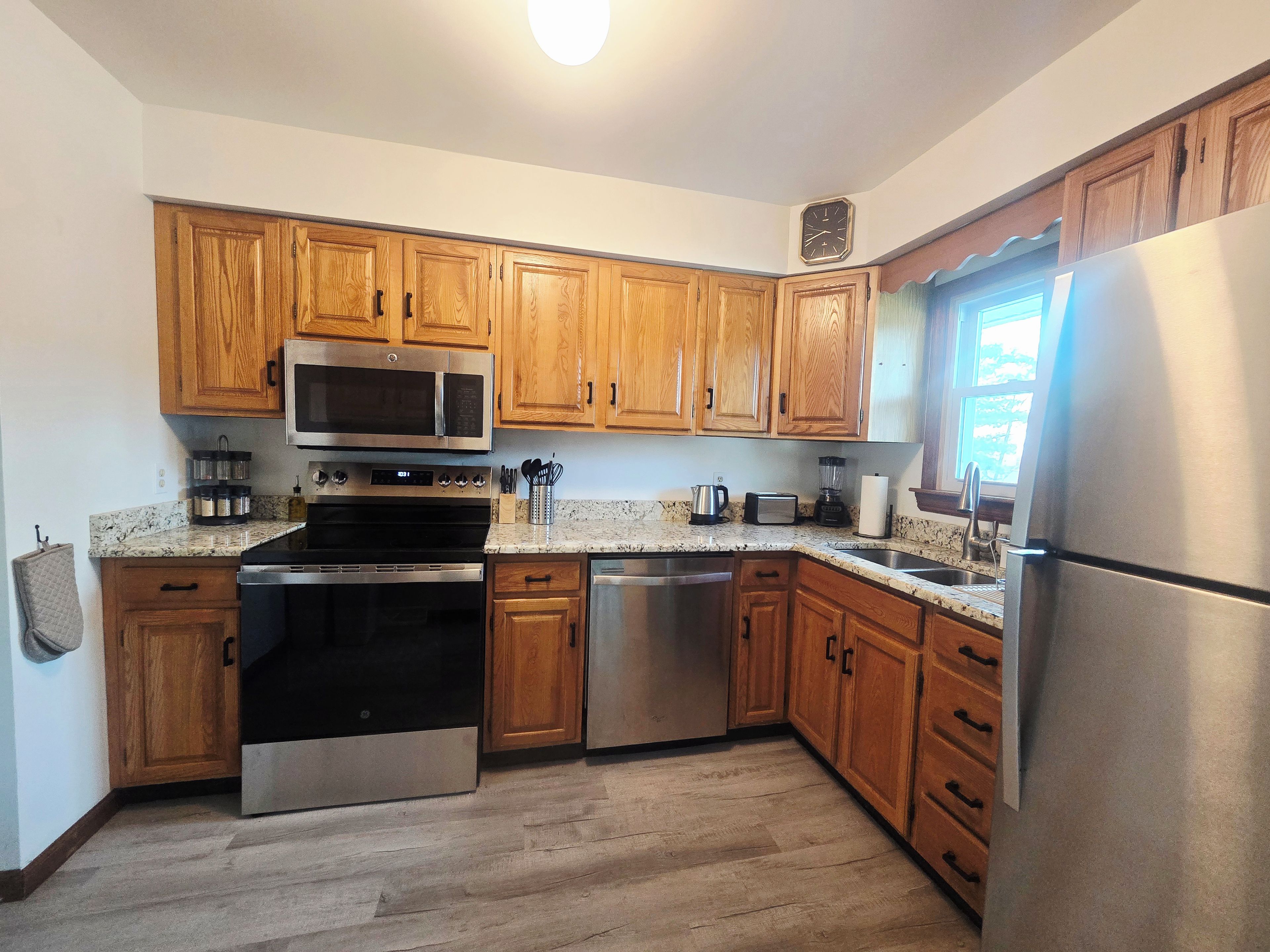 A kitchen with wooden cabinets, stainless steel appliances, a granite countertop, and a built-in oven.