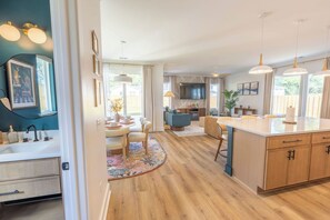 A modern kitchen with a central island, wooden cabinets, and pendant lighting. - Near Wrightsville, 3 Kings + Putting Green, Stylish Family & Group Getaway (Wilmington)
