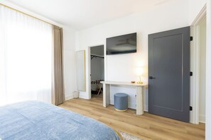 A bedroom with a bed, a bedside table with a lamp, a wardrobe, and a door. - Near Wrightsville, 3 Kings + Putting Green, Stylish Family & Group Getaway (Wilmington)