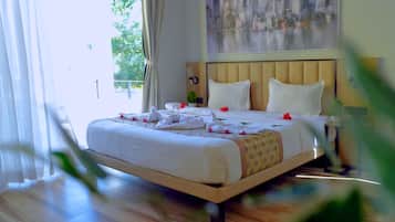 Habitación de hotel con cama, mesita de noche, un cuadro y vistas al exterior.