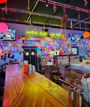 A bar area with a neon sign, shelves with bottles, and a bar counter. - Large Group Stay | Walk to St Augustine Downtown (St. Augustine)