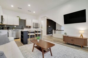 A modern kitchen with white cabinets, a built-in oven, and a dining area with a wooden table and chairs. - Large Group Stay | Walk to St Augustine Downtown (St. Augustine)