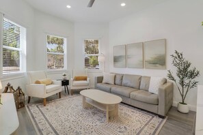 Ein modernes Wohnzimmer mit einer Couch, Sesseln, einem Couchtisch und Kunstwerken an der Wand.
