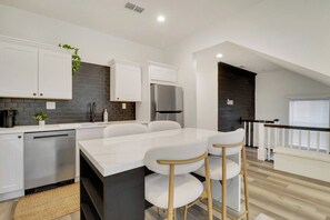 A modern kitchen with white cabinetry, a marble countertop, and a stainless steel refrigerator. - Walk to St Augustine | Fully Renovated Luxury Home (St. Augustine)
