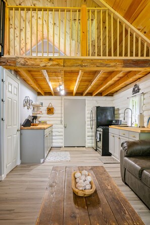A log cabin interior with a kitchen, dining area, and a loft bedroom. - Peaceful | Mountaintop Getaway | Solar Power (Springwater)