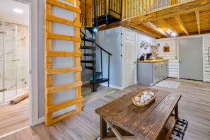 A wooden interior with a staircase, a kitchen area, and a dining table.