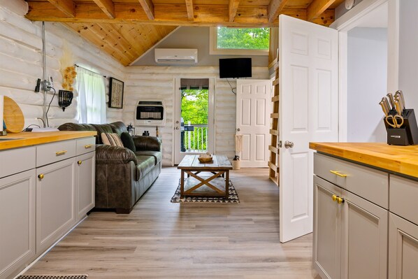 A log cabin interior with a living area, kitchen, and dining space.