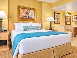 A hotel room with a large bed, a nightstand, a lamp, a painting on the wall, and a bathroom visible through an open door. - Bonnet Creek Resort - Spacious 1 BR Presidential near Lake Buena Vista (Lake Buena Vista)