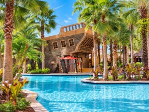 A pool area with a stone building, palm trees, and lounge chairs. - Bonnet Creek Resort - Spacious 1 BR Presidential near Lake Buena Vista (Lake Buena Vista)