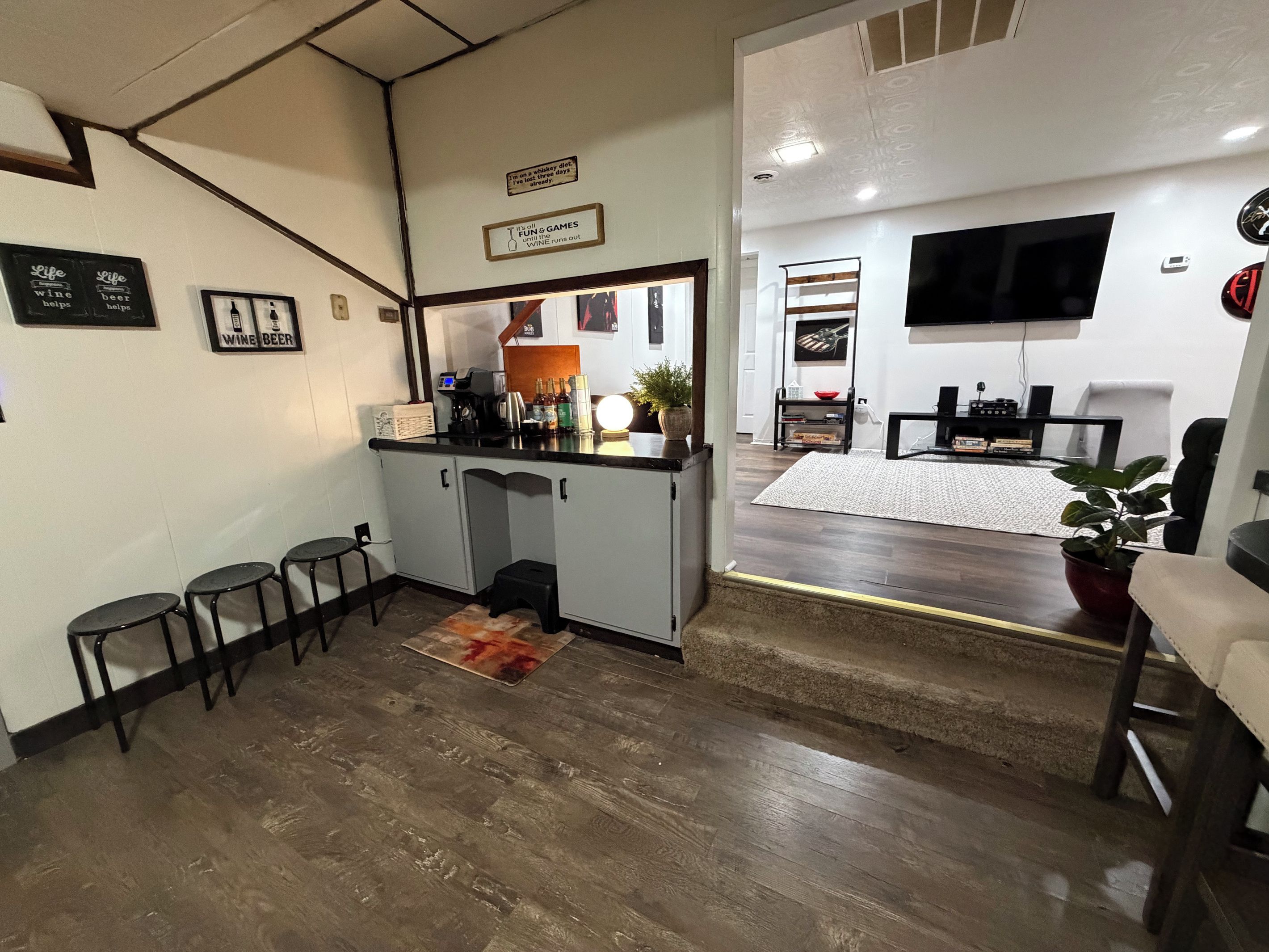 A compact living space with a kitchenette, seating area, and a TV mounted on the wall.