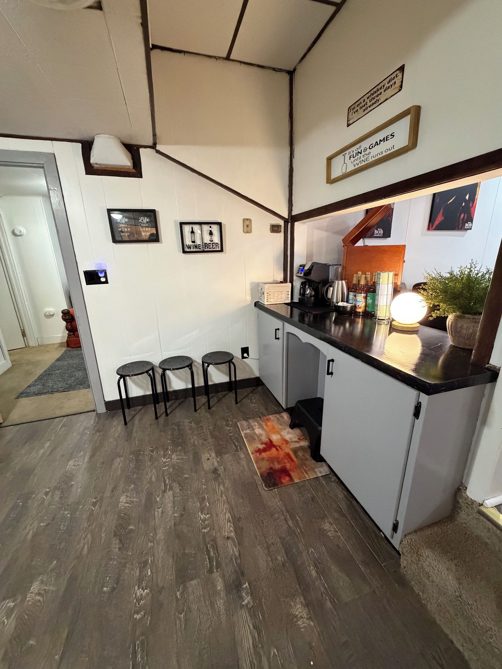 A compact kitchen with a bar area, stools, and a coffee machine.