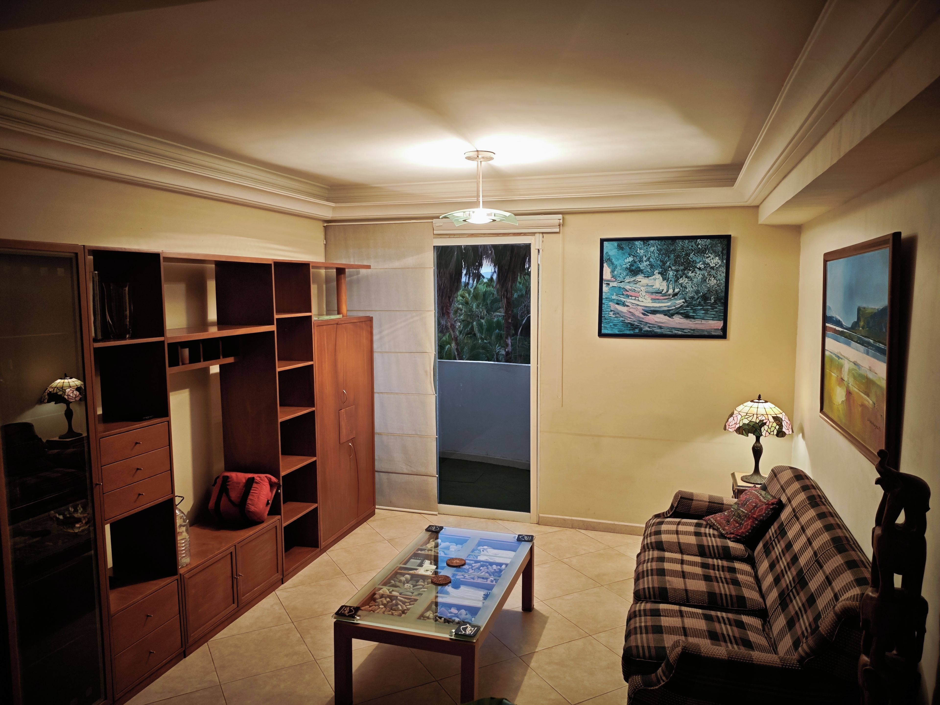 Una sala de estar con un sofá, una mesa de centro y un mueble de madera con estantes.