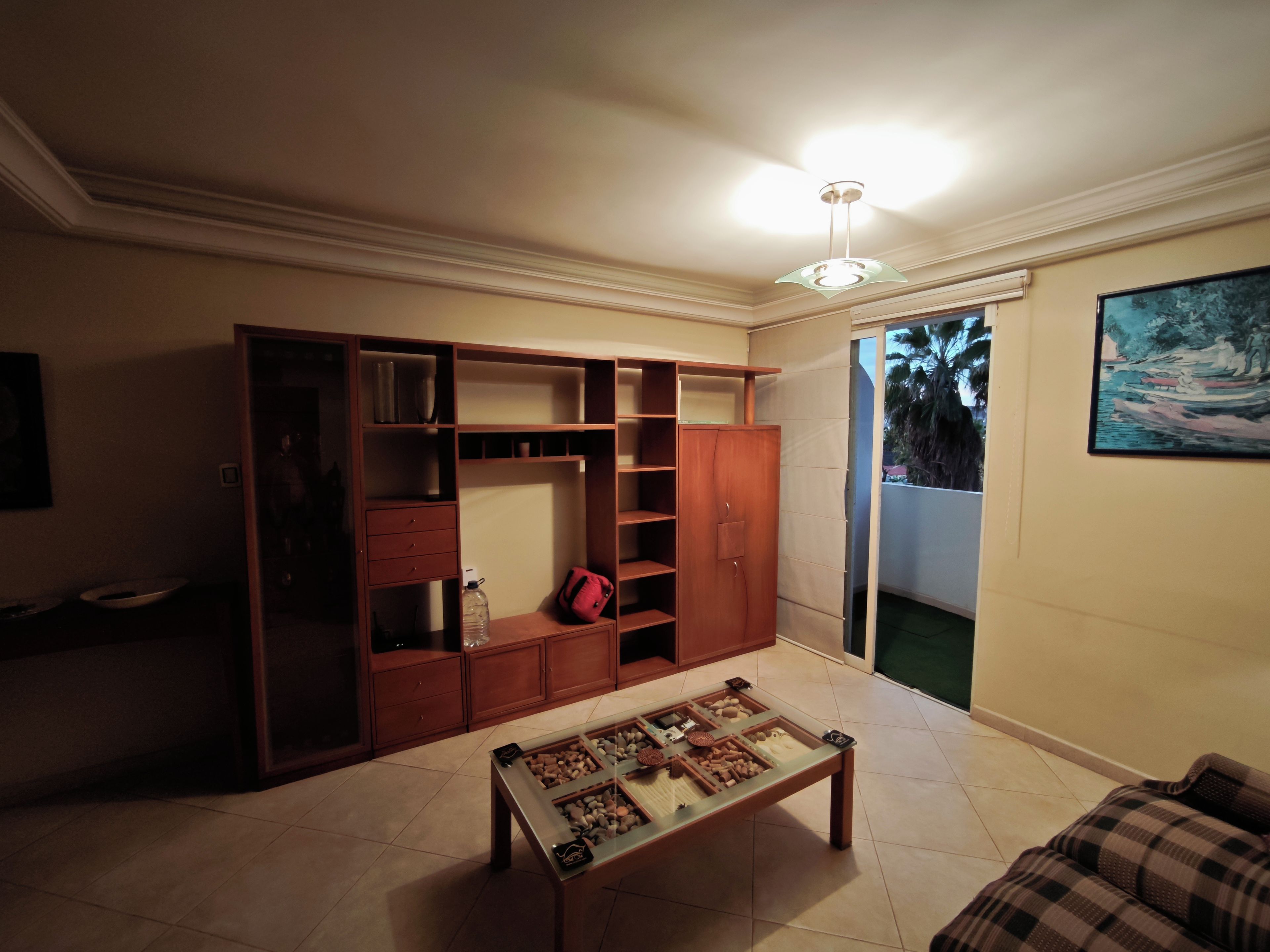 A room with a wooden cabinet, a glass coffee table, and a painting on the wall.