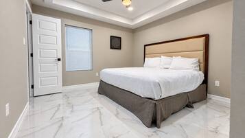 Une chambre à coucher avec un lit, un ventilateur de plafond et une fenêtre avec des stores.