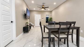 A dining area with a table and chairs, a ceiling fan, and a television on the wall.