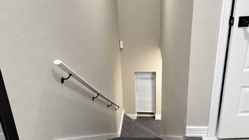 A staircase with a handrail, carpeted steps, and a door at the top.
