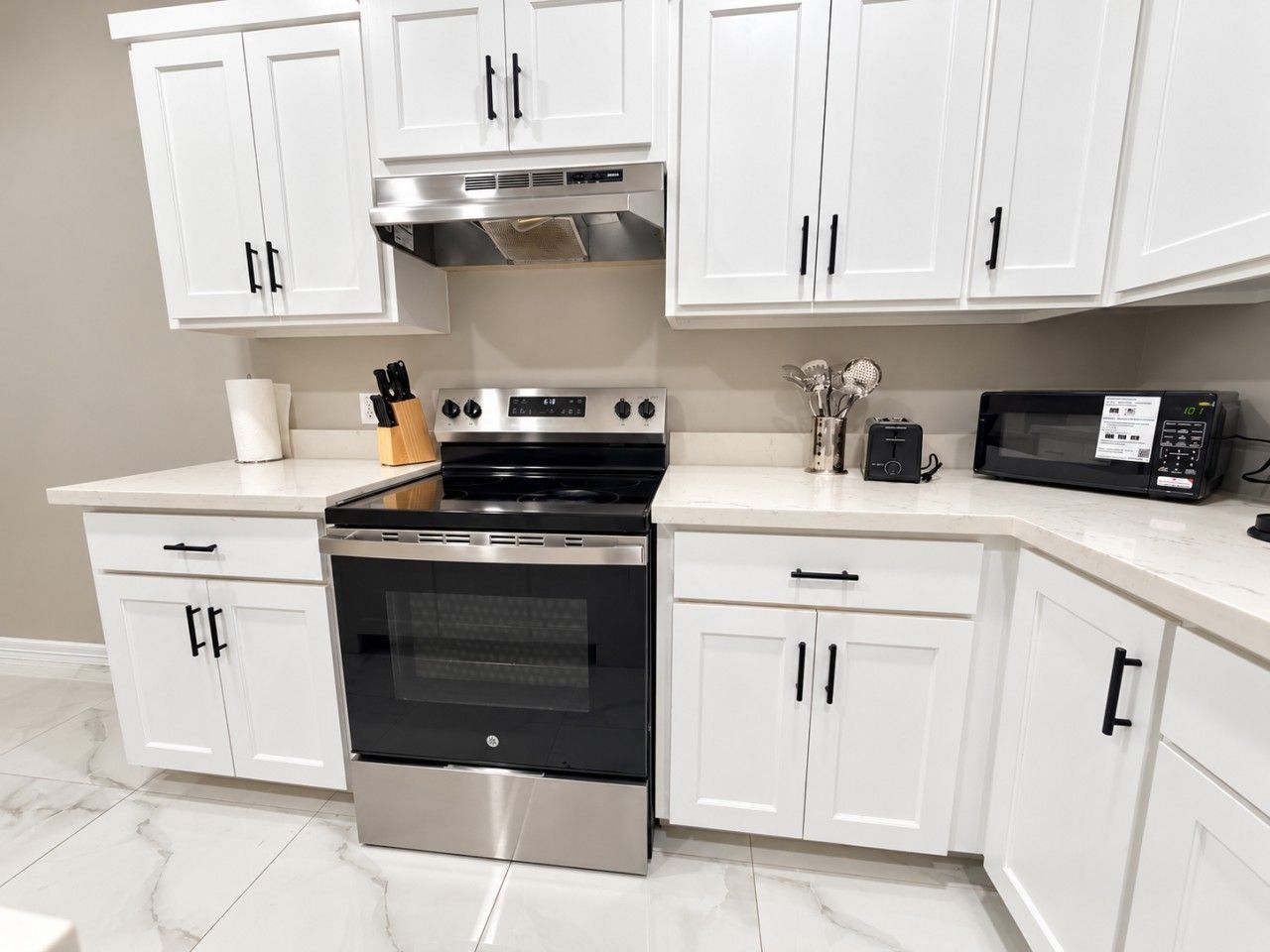 A kitchen with white cabinets, a stainless steel oven, and a microwave.