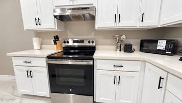 A kitchen with white cabinets, a stainless steel oven, and a microwave.