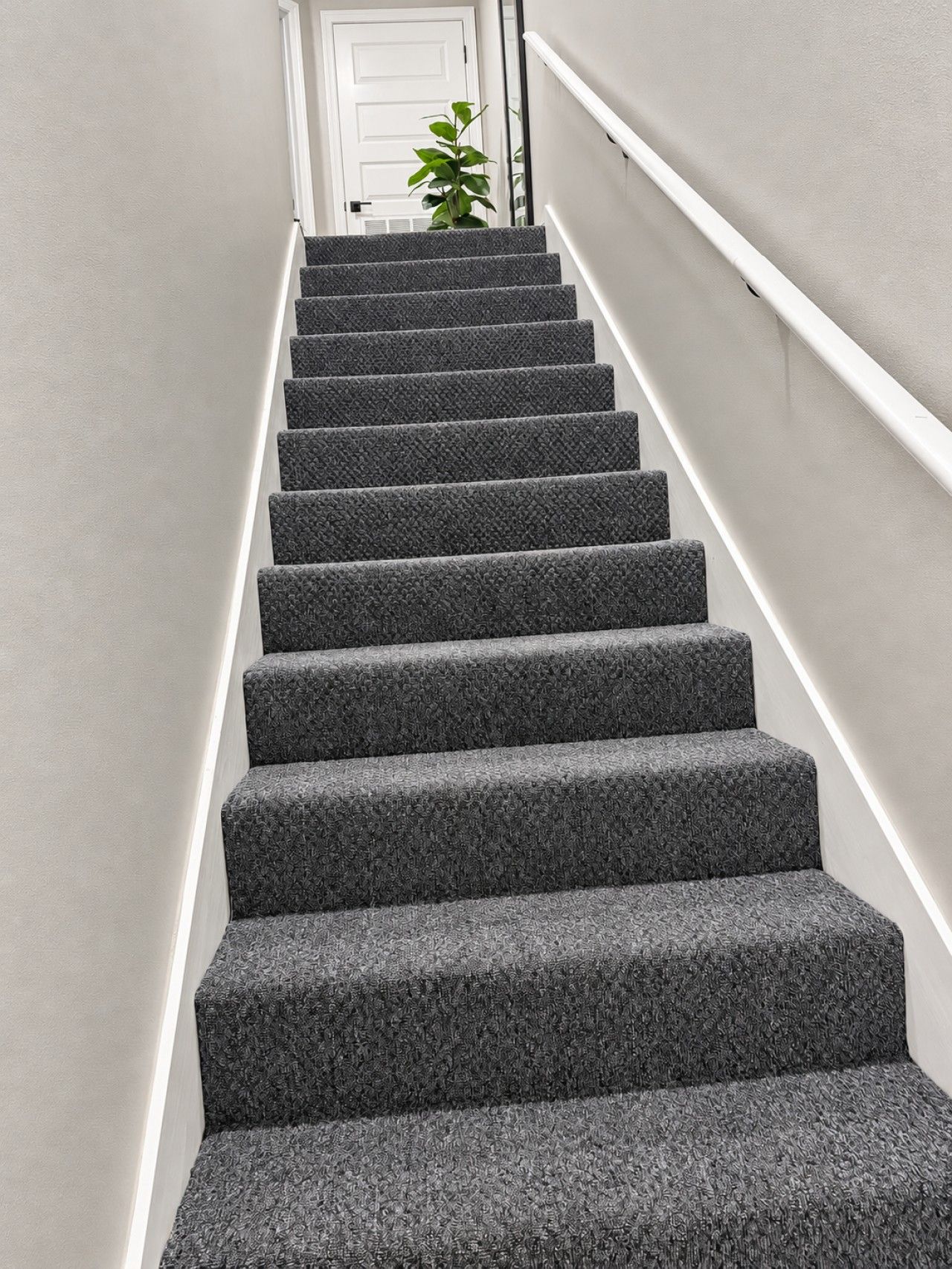 A staircase with carpeted steps leading up to a white door.