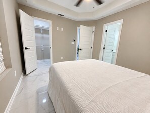 A bedroom with a large bed, two doors, and a ceiling fan.