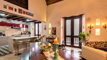 Una cocina moderna con taburetes de bar, una mesa de comedor con velas y un sofá en una sala de estar acogedora.