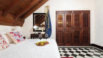 Une chambre à coucher avec un lit, une armoire en bois, un miroir et une petite table avec une lampe.