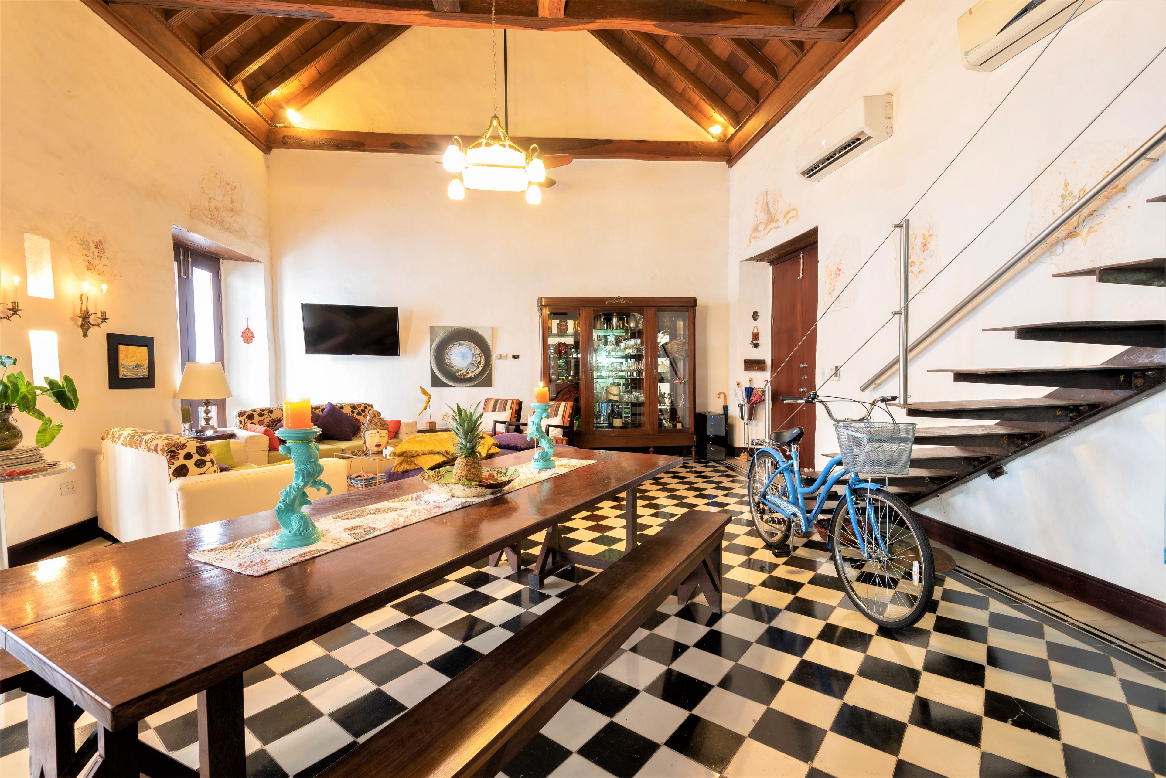 Un coin repas avec un sol à carreaux, une longue table et un vélo.