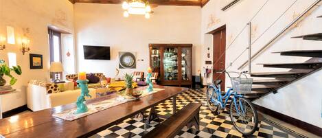 Un comedor con piso a cuadros, una mesa larga y una bicicleta.