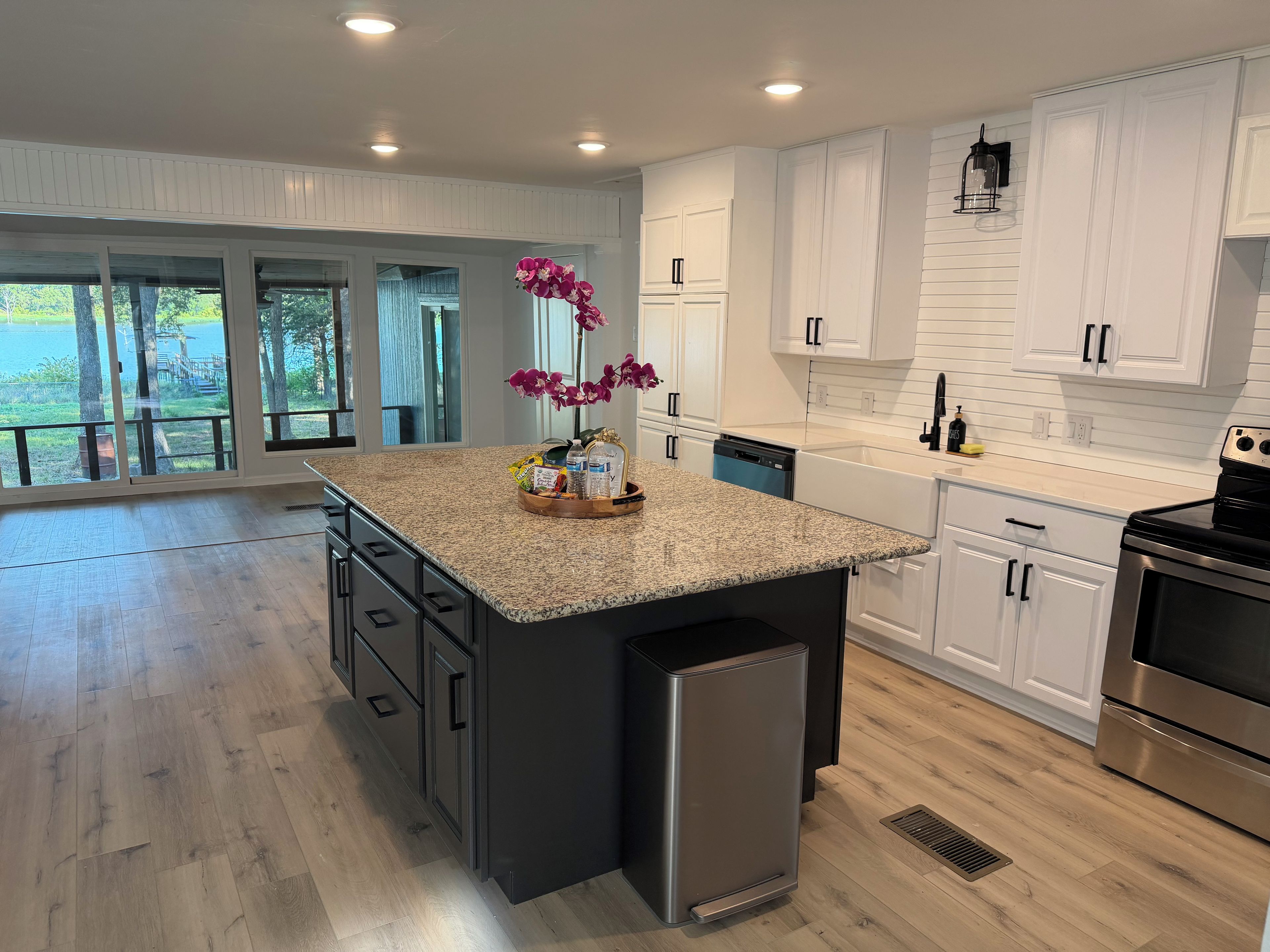 A modern kitchen with a granite countertop, stainless steel appliances, and white cabinetry.