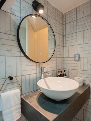 A bathroom with a round mirror, a white sink, and a towel rack. - Stylish 2BR in Polanco with King Bed and Workspace (Mexico City)