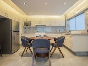 A modern kitchen with a central island, built-in appliances, and a dining area with chairs. - Stylish 2BR in Polanco with King Bed and Workspace (Mexico City)