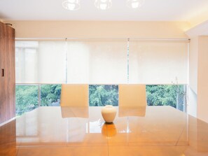 Ein modernes Zimmer mit großem Fenster, glänzendem Boden und einer zentral platzierten Vase.