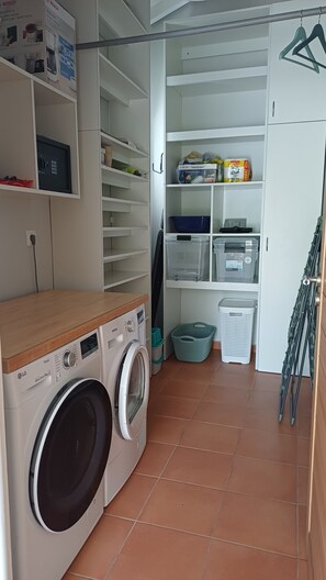 A laundry area with a washing machine, shelves with storage bins, and a drying rack. - New Listing (Saint-François)
