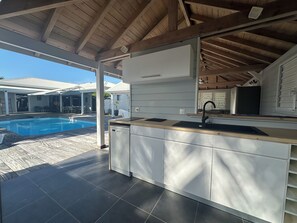 A covered outdoor kitchen area with a pool in the background. - New Listing (Saint-François)
