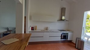 A modern kitchen with white cabinets, a stainless steel range hood, and a built-in oven. - New Listing (Saint-François)