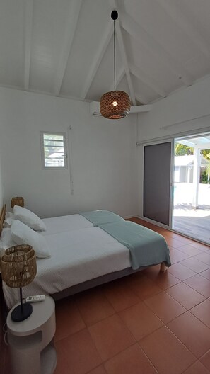 Ein Schlafzimmer mit Bett, Nachttisch, Lampe und Fenster.