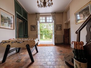 Ein Zimmer mit Kicker, Heizkörper, Holzstuhl, Treppe und Blick ins Freie.