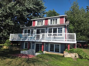 A two-story house with a balcony, large windows, and a red and white color scheme.