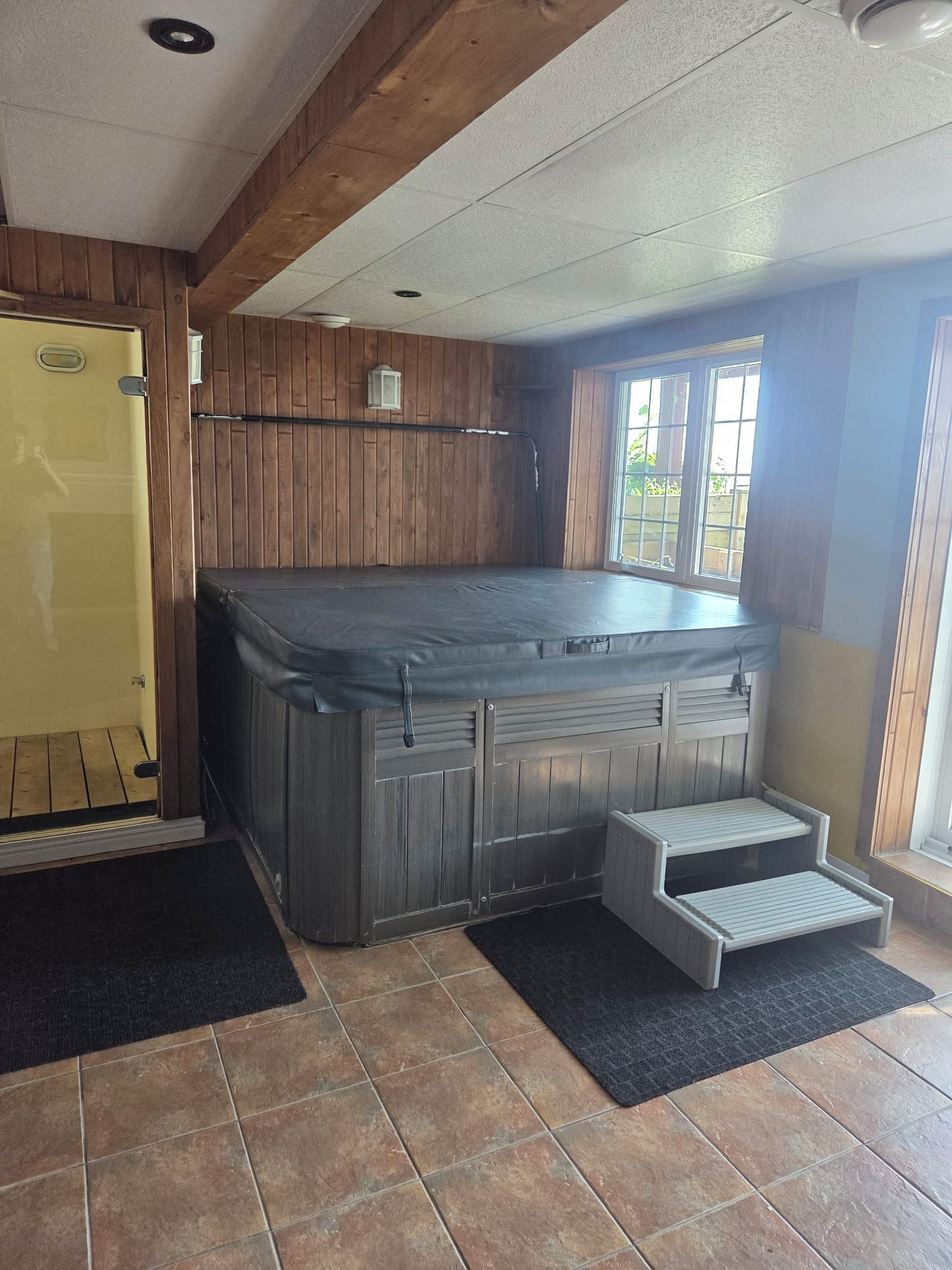 A hot tub in a room with wooden walls and a window.