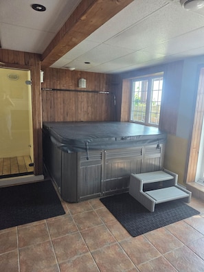 A hot tub in a room with wooden walls and a window.