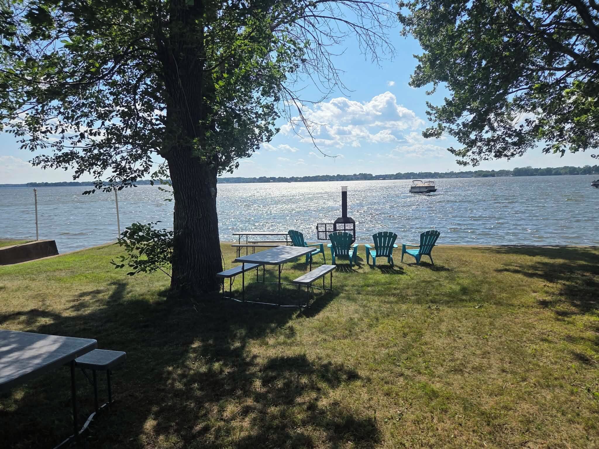 A lakeside outdoor seating area with tables, chairs, and a grill.