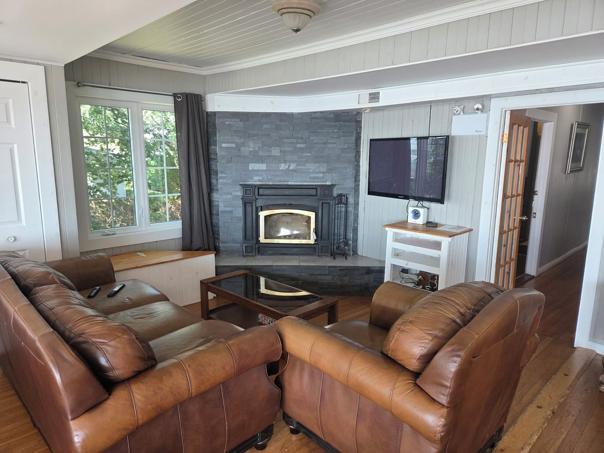 A living room with leather sofas, a fireplace, a television, and a wooden coffee table.