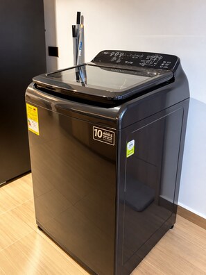 A black washing machine with a digital control panel, a 10-year warranty label, and a yellow energy efficiency sticker. - New Listing (Medellín)